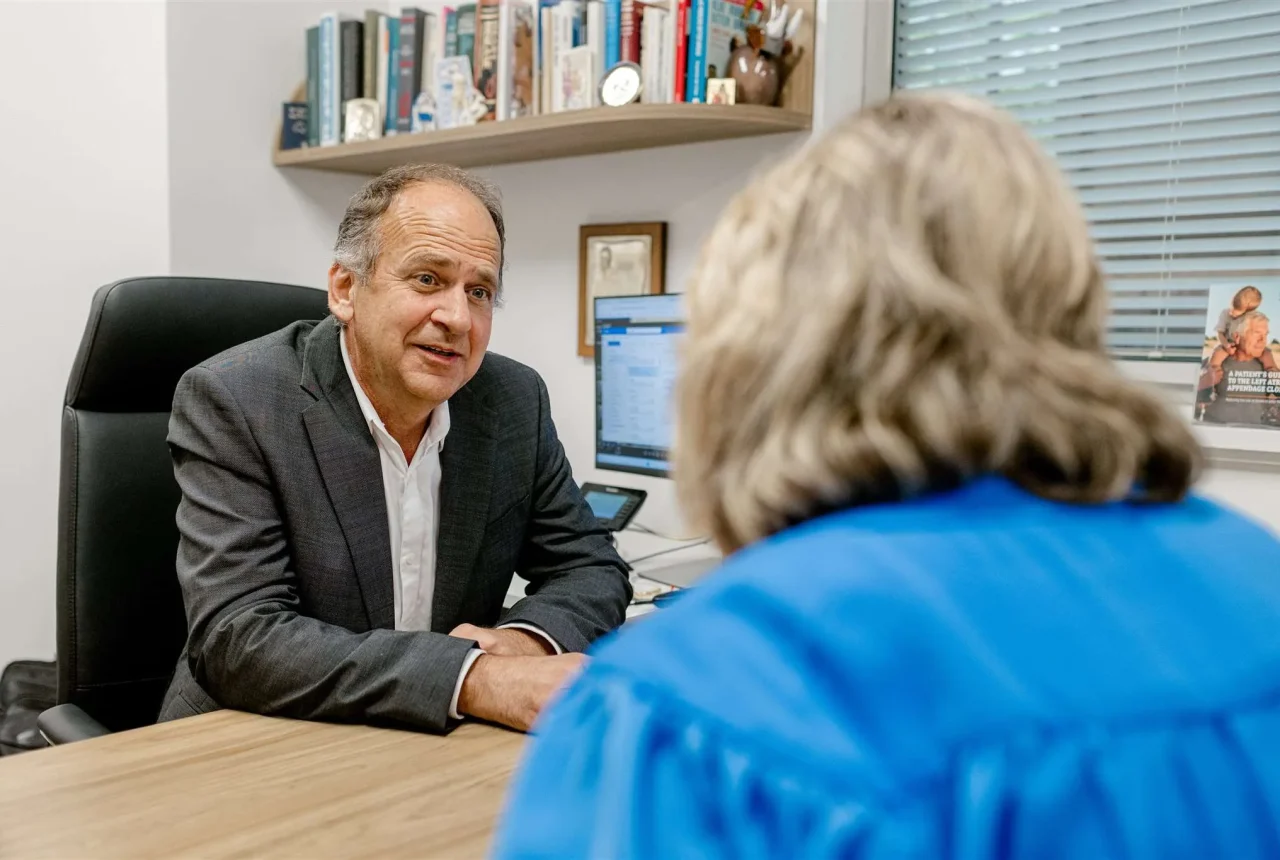 Dr Hadjipetrou at his desk talking to a patient