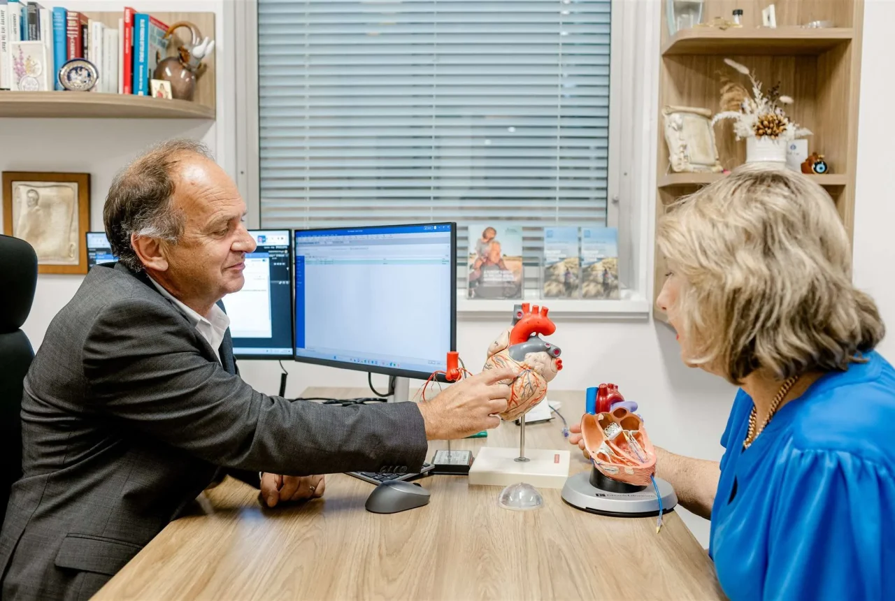 Dr Hadjipetrou with a patient pointing at a human heart anatomic model