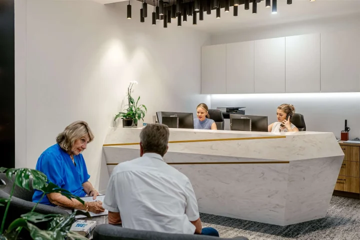 Two patients sitting in the waiting room of the clinic in front of the main desk